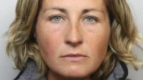 Nerys Lloyd mug shot taken when she was arrested. She has blue eyes and chin length blonde wavy hair and is looking straight ahead. 