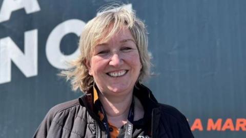 Laura Sawyer, who has shoulder length blonde hair and is wearing a black jacket and polo shirt.