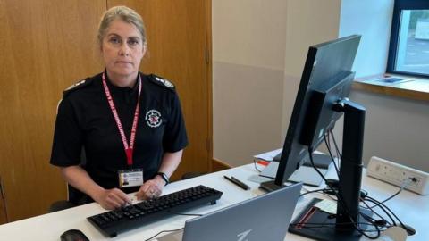 Nikki Watson with fair hair sitting at a desk with a computer