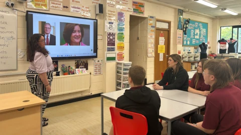 Disgyblion Ysgol Uwchradd y Gellifedw yn edrych ar fwrdd gwyn gyda lluniau Eluned Morgan a Keir Starmer