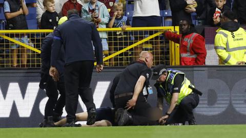 A man being restrained at the match between Burnley and Manchester City
