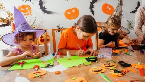 Three children decorating for Halloween