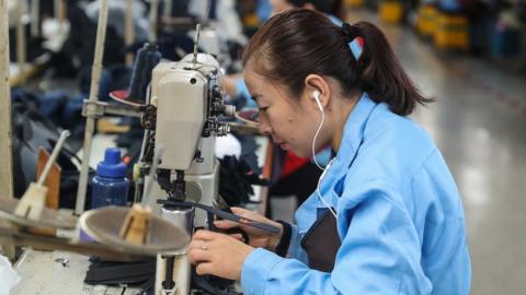 A woman sews shoes in a factory in China