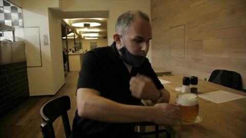 Rob Cameron lowers his mask to sip beer at a brewery in Prague