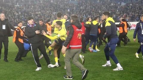 Players and fans clash on the pitch after the game between Trabzonspor and Fenerbahce