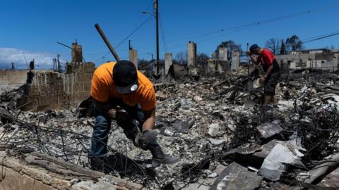 Lester (L) searches for the urn with the ashes of his son in the ruins of what once was his bedroom next to Lotario (R) the owner of the house destroyed by a wild fire in Lahaina, Hawaii, USA, 11 August 2023.