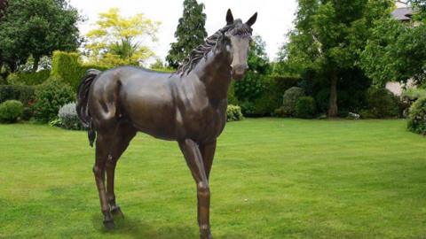 A bronze statue of a horse in a field