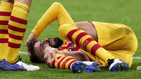 Gerard Pique holds his knee as he awaits treatment on the pitch