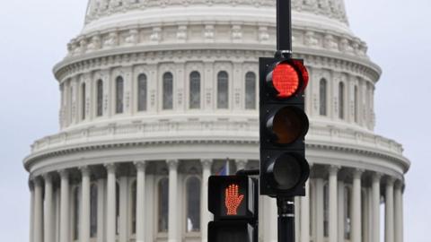 A stoplight is seen in front of the dome of the US Capitol