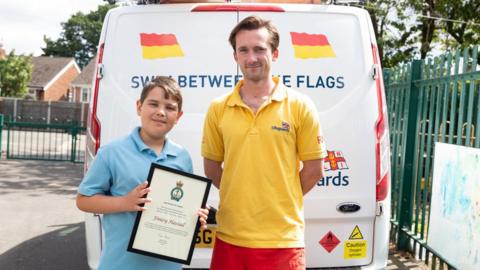 Finley holding a certificate next to the lifeguard Guy Potter