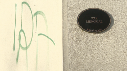 IRA painting on a wall next to sign that read "WAR MEMORIAL"