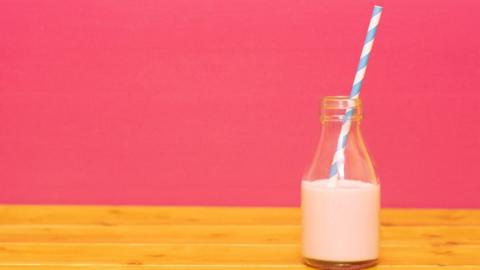 glass bottle of milk on pink background 