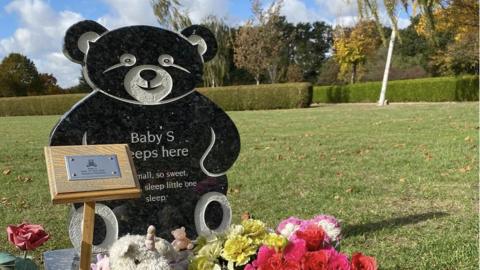 Baby S teddy bear shaped headstone and flowers