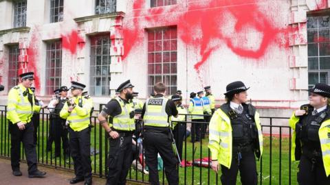 Police officers at the Ministry of Defence after red paint is thrown at the building's walls