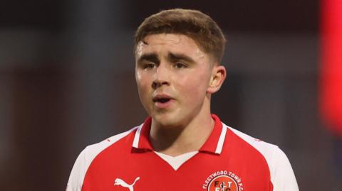 Harrison Neal wears a red and white Fleetwood Town shirt while in action for the club.