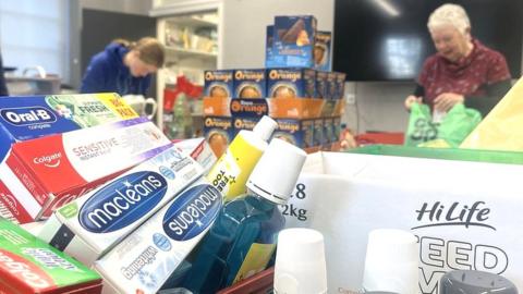 Toiletries on a table with volunteers packing them