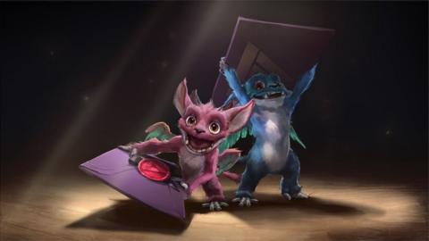 Two little monsters hold playing cards in this promotion image