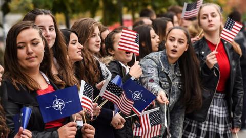 Kosovo Albanian youth wave US and NATO flags during a US Army and Kosovo Security Force running competition in Pristina on 20 October 2016.