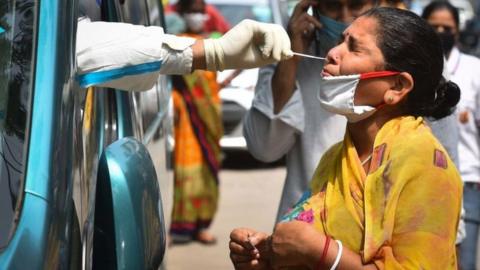 A health worker of Special Mobile Surveillance team in PPE coveralls collects a swab sample from a woman for Covid-19 rapid antigen test, at Model Town, on July 15, 2020 in New Delhi, India