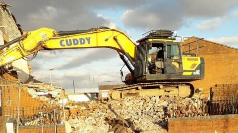 A digger knocking down a building