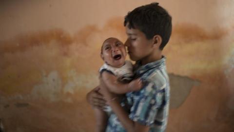 10-year-old Elison nurses his 2-month-old brother Jose Wesley at their house in Poco Fundo, Pernambuco state, Brazil