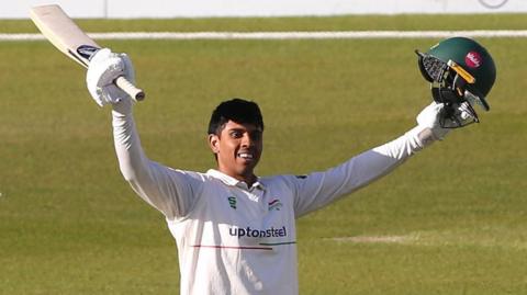 Rishi Patel raises his arms after scoring a century for Leicestershire