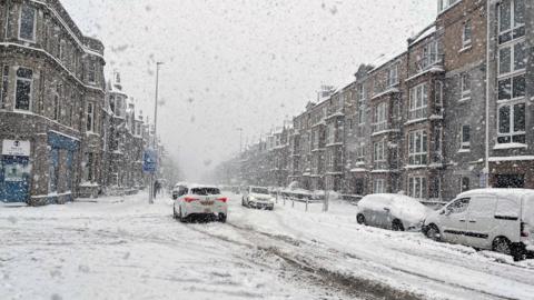 Big flakes of snow fall on a snow-covered street in Inverness on 5 January this year.