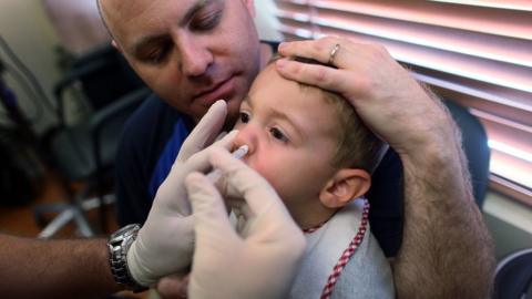 A two-year-old receiving the nasal spray vaccine