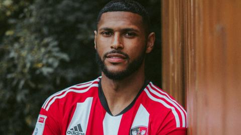 Zak Jules poses in an Exeter City kit after joining the club