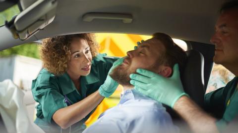 Two ambulance paramedics stabilise a car crash victim