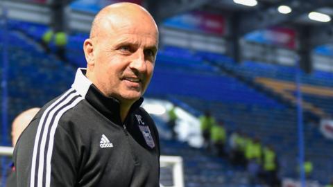 Ex-Portsmouth boss Paul Cook walks onto the field at Fratton Park.