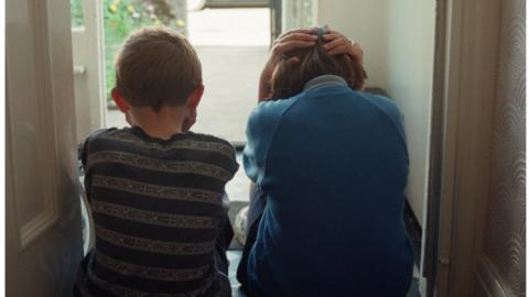 Children sitting on a porch with their backs turned to the camera