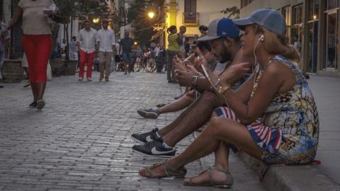 People use public WiFi to connect their devices in a street of Havana