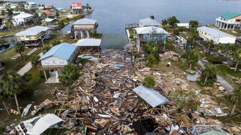 An aerial view of damaged houses next to the coast