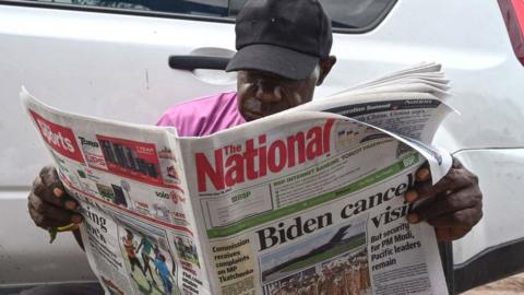 A man reads a newspaper reporting on the cancellation of a visit to Papua New Guinea by US President Joe Biden in Port Moresby on May 18, 2023.