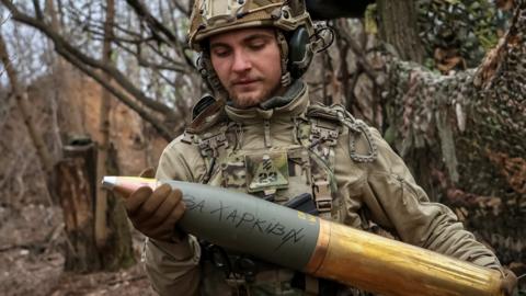 A Ukrainian serviceman prepares a shell with an inscription 'for Kharkiv' for a howitzer at a position in a front line, in Donetsk region, Ukraine, April 5, 2024
