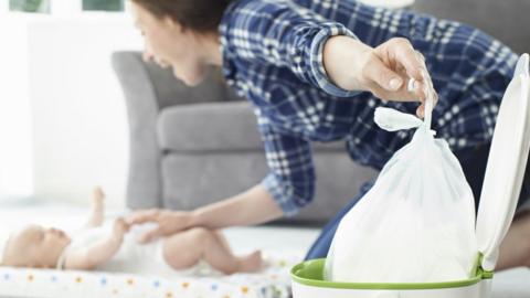 Nappy being put in a bin as a baby is changed