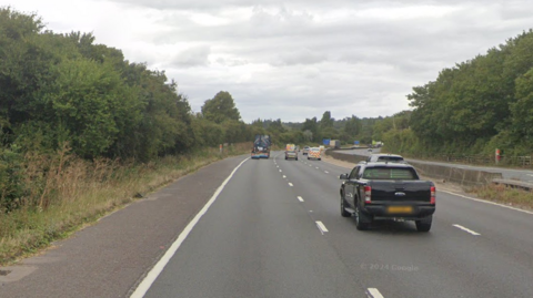 A part of the A1 (M) northbound, it has a number of cars travelling on it and the hard shoulder is visible.