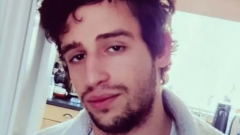 The head and shoulders of Pawel Martyniak looking directly at the camera. He is wearing a white or grey fleece and has messy brown hair.