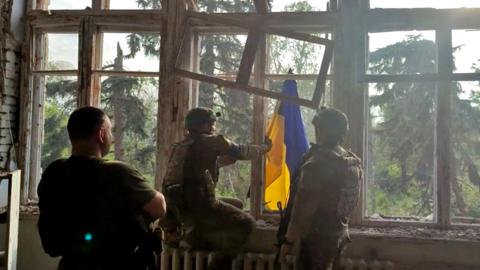 Ukrainian soldiers place a Ukrainian flag at a building, during an operation that claims to liberate the first village amid a counter-offensive, in a location given as Blahodatne, Donetsk Region, Ukraine, in this screengrab taken from a handout video released on 11 June 2023