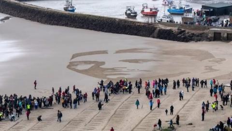 Face of Wilfred Owen drawn in sand