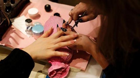 An image of someone having the nails on one of their hands manicured.