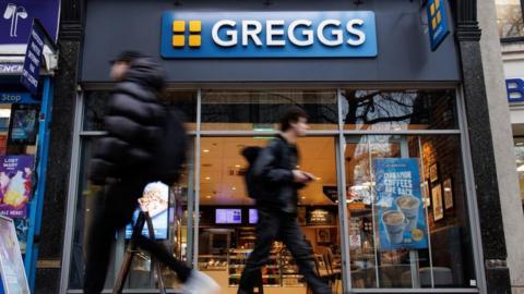 A Greggs store in London, with people walking briskly past