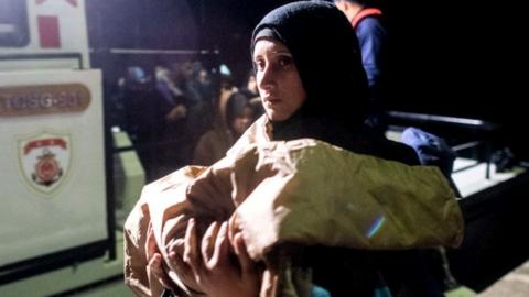 A migrant woman carries her baby after getting off a boat bound for the Greek island of Kos, 15 November 2019