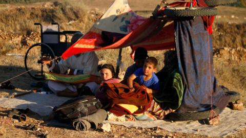 Displaced Syrians from the Deraa province wait in a makeshift camp near the town of Nassib to cross the Jordanian border (1 July 2018)