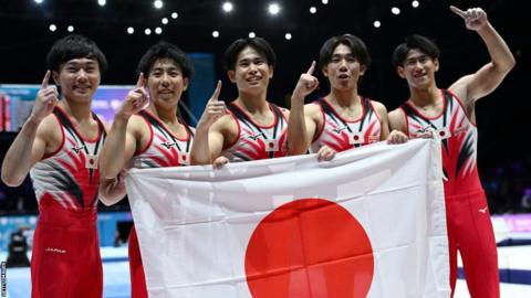 Japan celebrate by holding a flag after winning gold