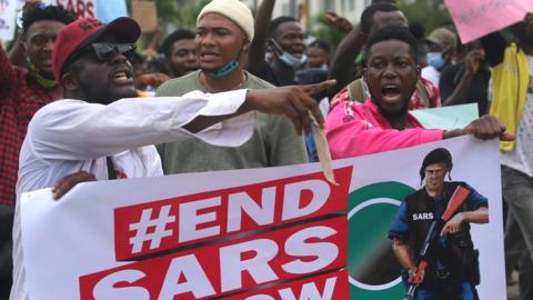 Protesters shout slogans as they hold a banner with the inscription "End SARS now"