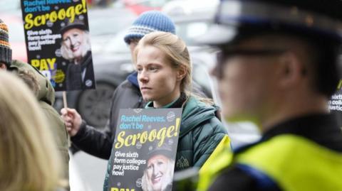 Members of the National Education Union outside Rachel Reeves' office holding placards which read: "Rachel Reeves don't be a Scrooge". Ms Reeves is depicted on the placard dressed in the clothing and hair of the fictional character created by Charles Dickens.