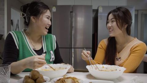 Myung-hui and daughter Songmi eat noodles together, smiling