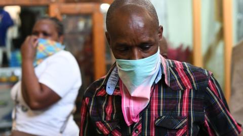 A curio trader covers his nose at the market in Nairobi